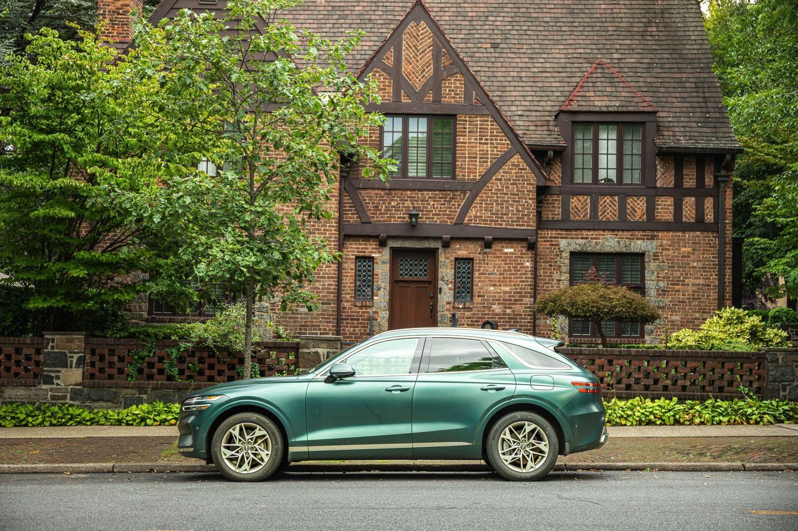 A green SUV parked outside a brick house